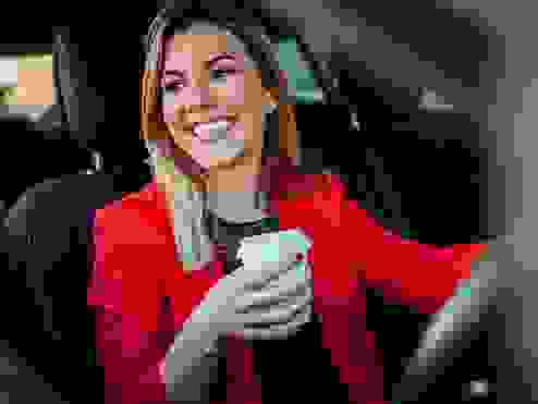 woman driving a car holding a coffee mug in her hand